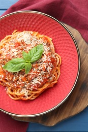 Photo of Delicious pasta bolognese with basil on blue table, top view