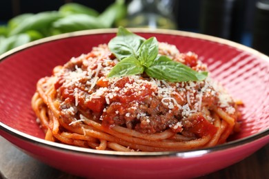 Photo of Delicious pasta bolognese with basil on table, closeup