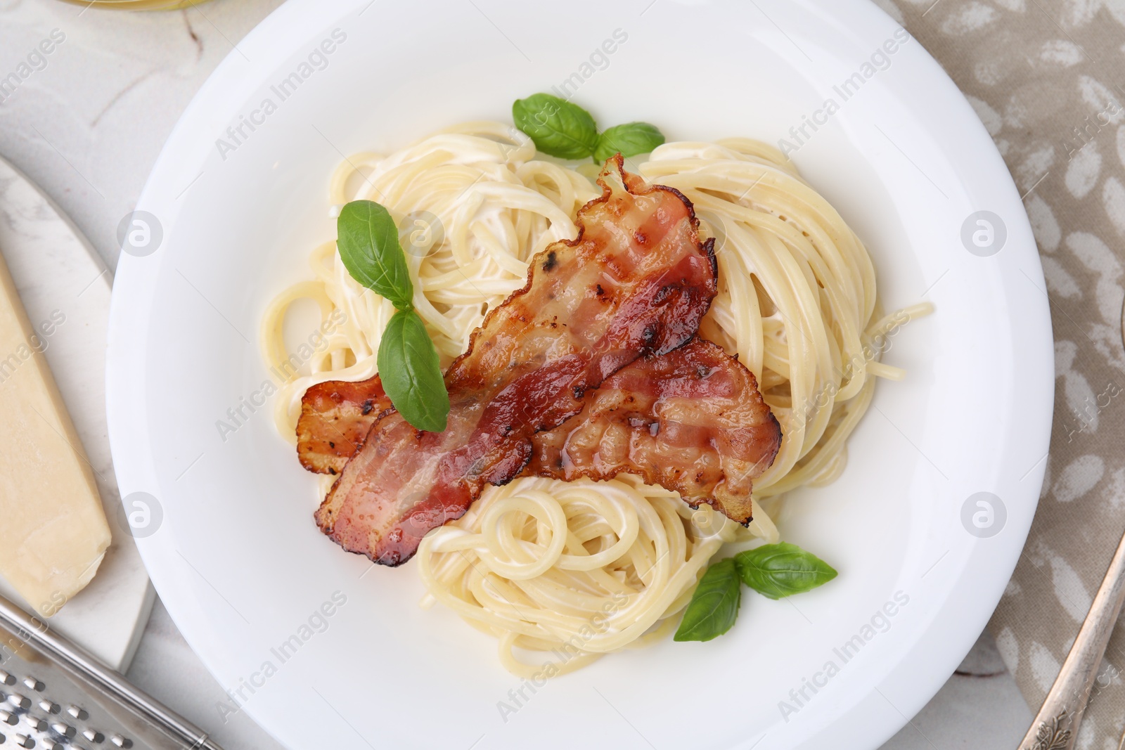 Photo of Delicious pasta Carbonara with bacon and basil on table, top view