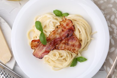 Photo of Delicious pasta Carbonara with bacon and basil on table, top view