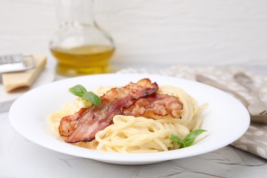 Photo of Delicious pasta Carbonara with bacon and basil on light table, closeup