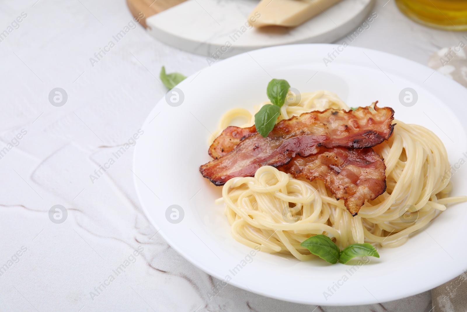 Photo of Delicious pasta Carbonara with bacon and basil on light textured table, closeup