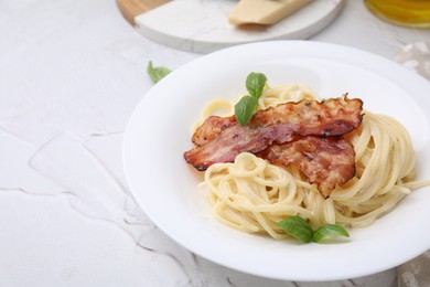 Delicious pasta Carbonara with bacon and basil on light textured table, closeup