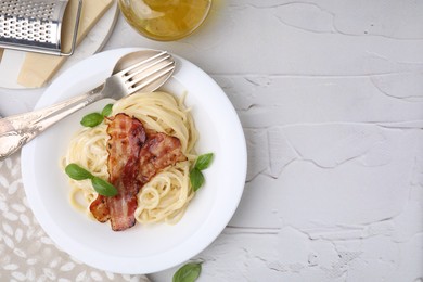 Delicious pasta Carbonara, cheese, oil, cutlery and grater on light textured table, flat lay. Space for text