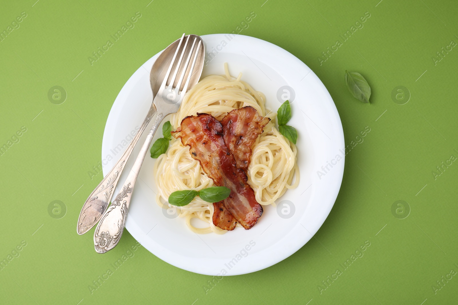 Photo of Delicious pasta Carbonara served on green table, top view