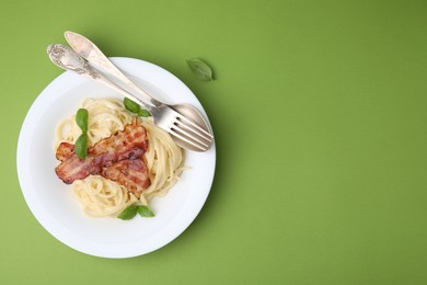 Delicious pasta Carbonara served on green table, top view. Space for text