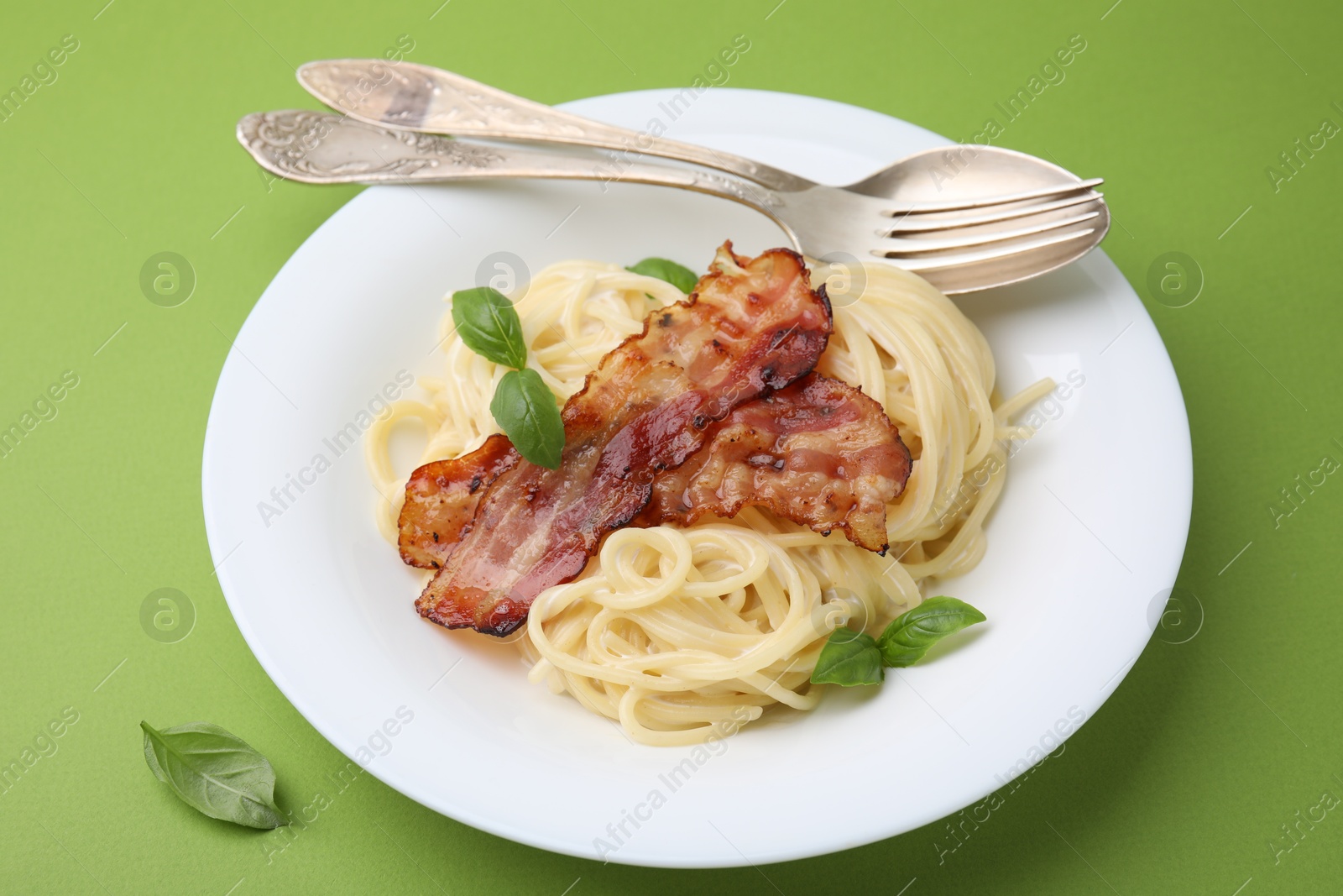 Photo of Delicious pasta Carbonara served on green table, closeup