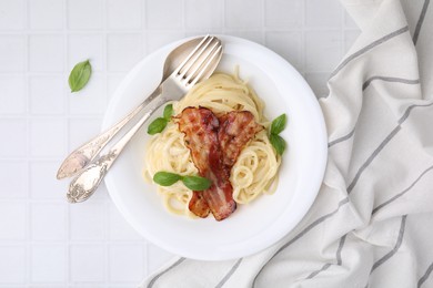 Delicious pasta Carbonara served on white tiled table, top view