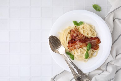 Photo of Delicious pasta Carbonara served on white tiled table, top view. Space for text