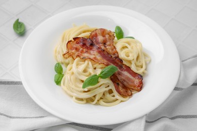 Photo of Delicious pasta Carbonara with bacon and basil on white tiled table, closeup