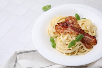 Photo of Delicious pasta Carbonara with bacon and basil on white tiled table, closeup