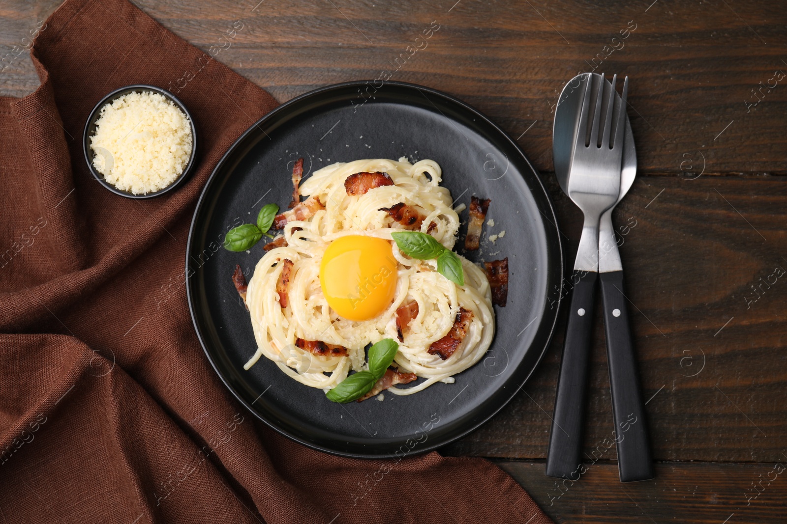 Photo of Delicious pasta Carbonara served on wooden table, flat lay