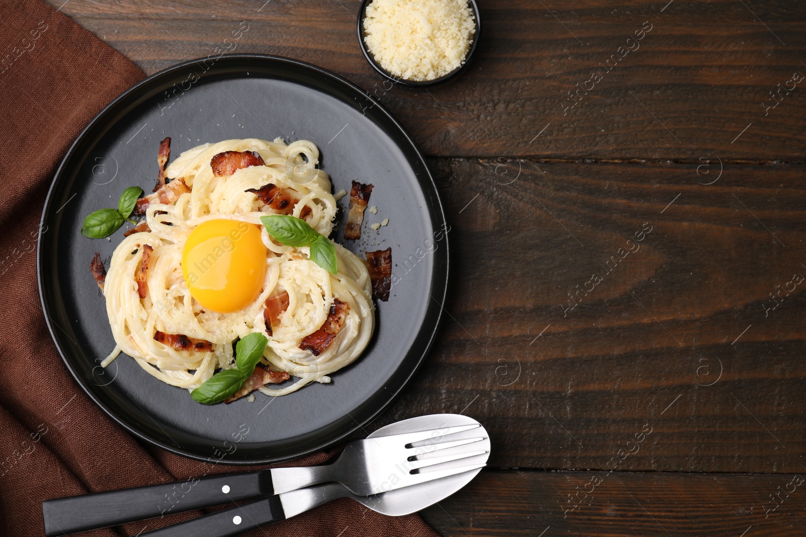 Photo of Delicious pasta Carbonara served on wooden table, flat lay. Space for text