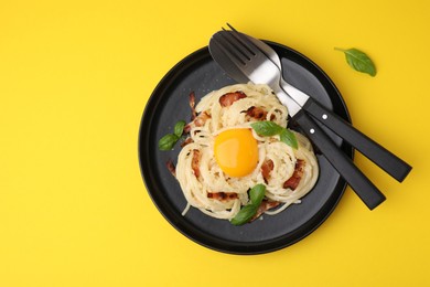 Photo of Delicious pasta Carbonara served on yellow table, top view. Space for text