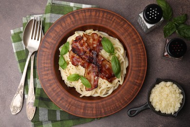 Photo of Delicious pasta Carbonara served on brown table, flat lay