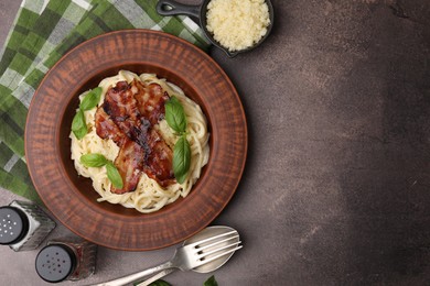 Photo of Delicious pasta Carbonara served on brown table, flat lay. Space for text