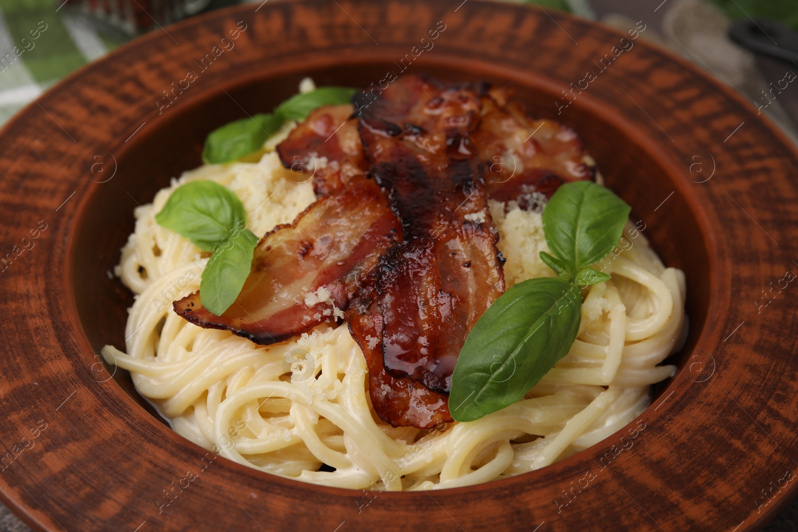 Photo of Delicious pasta Carbonara with bacon and basil on plate, closeup