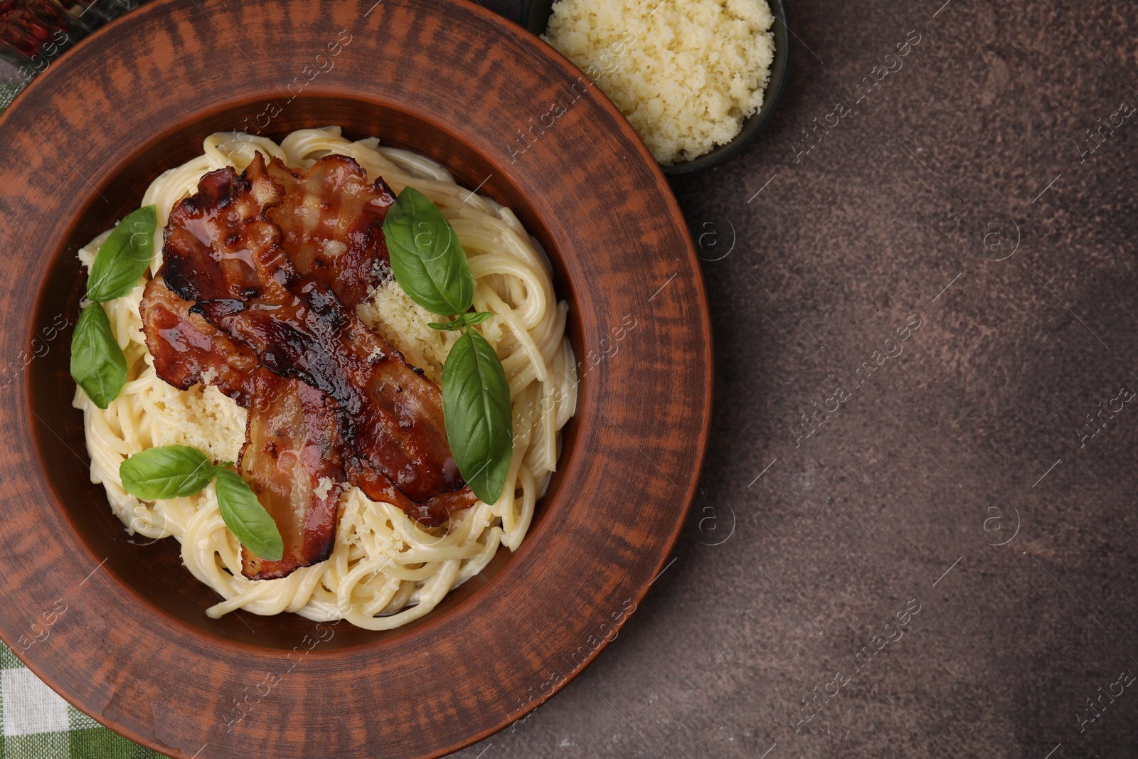 Photo of Delicious pasta Carbonara with bacon, basil and cheese on brown table, flat lay. Space for text