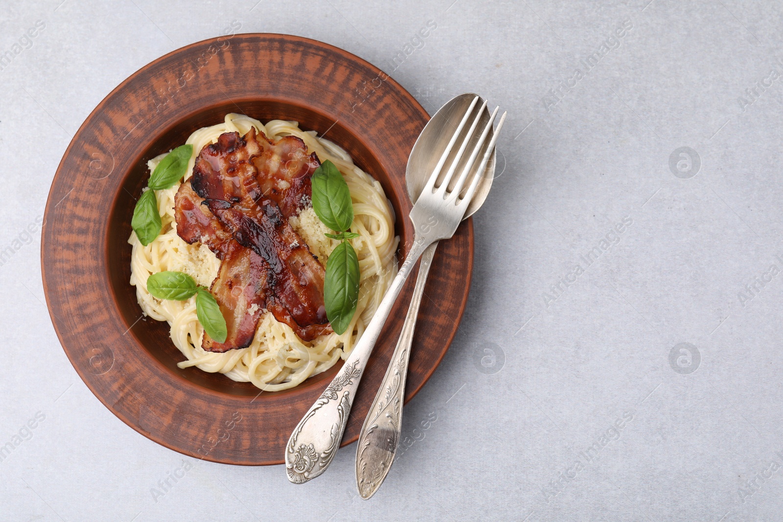 Photo of Delicious pasta Carbonara served on light gray table, top view. Space for text