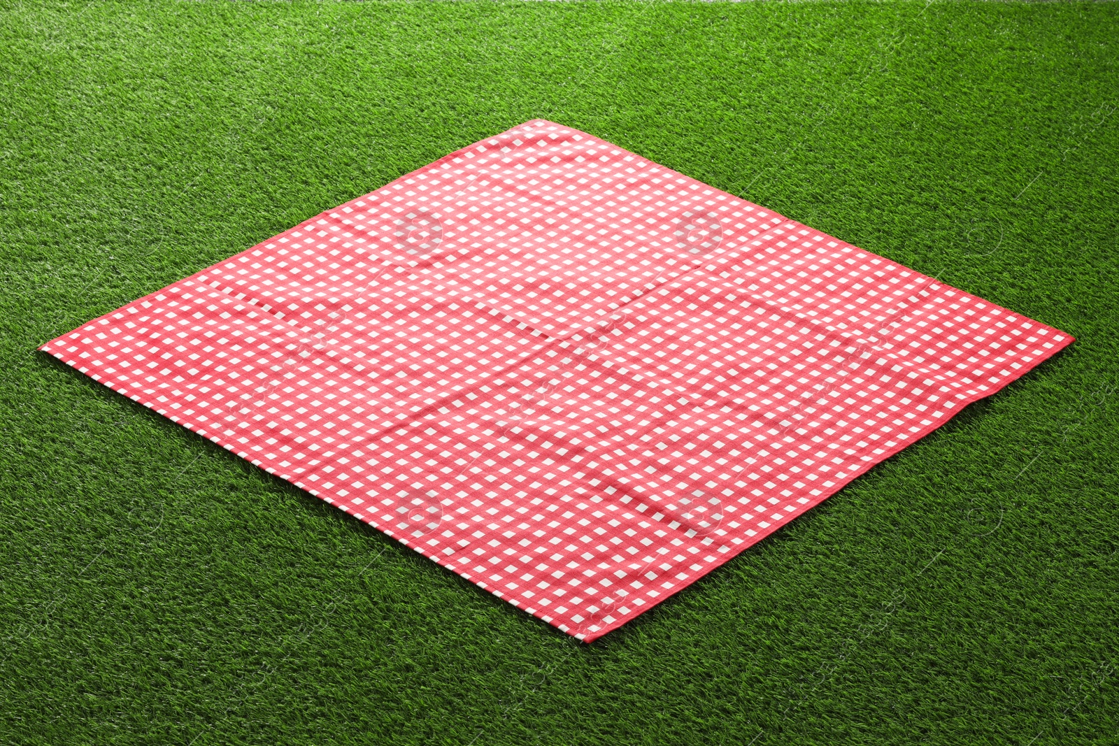 Photo of Red checkered picnic tablecloth on green grass