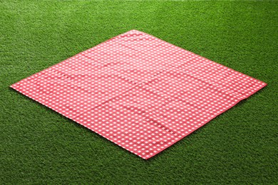 Photo of Red checkered picnic tablecloth on green grass