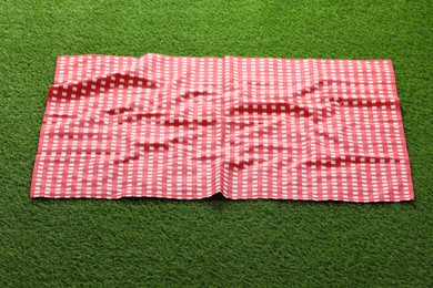 Photo of Red checkered picnic tablecloth on green grass