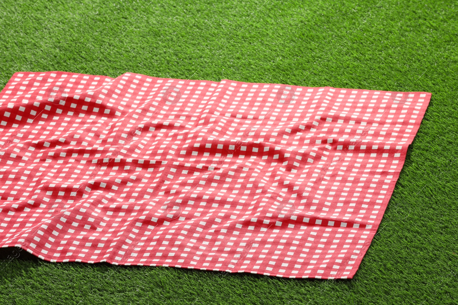 Checkered picnic tablecloth on green grass, closeup Photo of Checkered picnic tablecloth on green grass, closeup