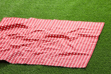 Photo of Checkered picnic tablecloth on green grass, closeup