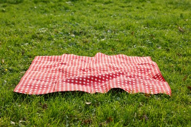 Photo of One checkered picnic tablecloth on green grass