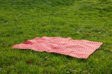 Photo of One checkered picnic tablecloth on green grass