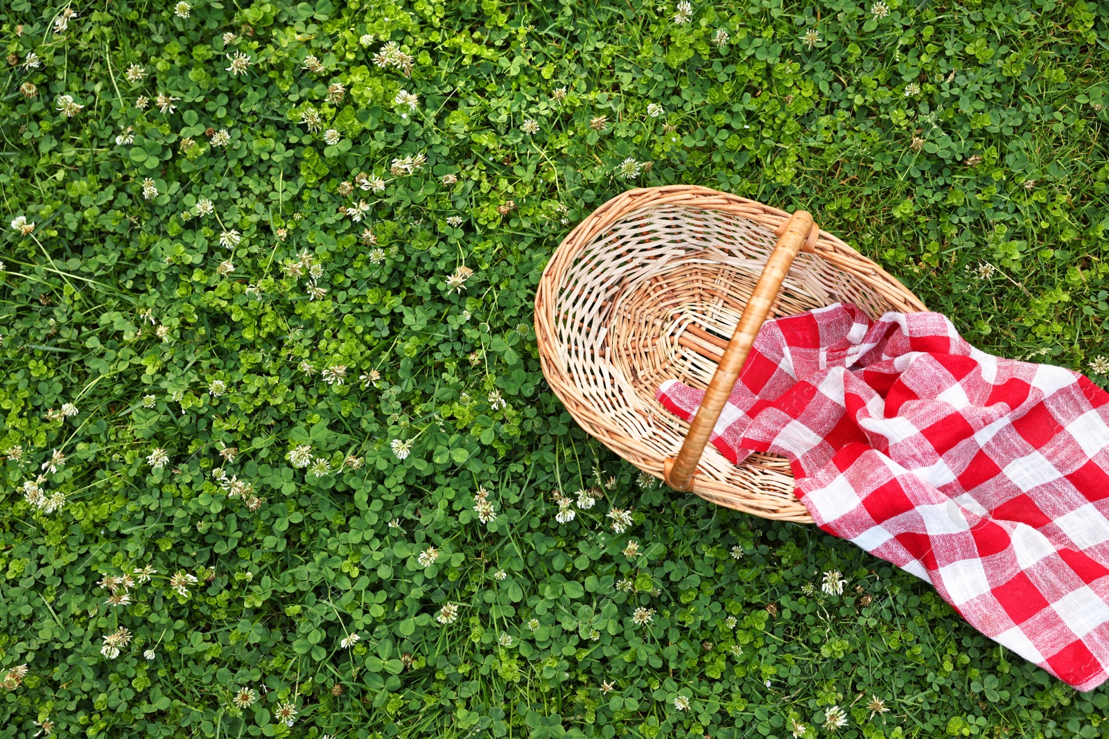 Photo of One picnic wicker basket on green grass, top view. Space for text