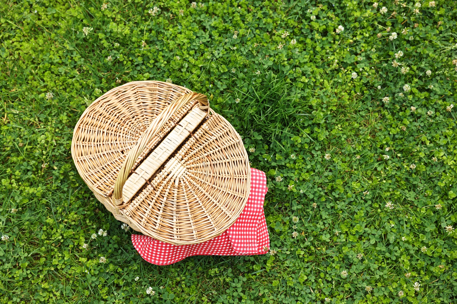 Photo of One picnic wicker basket on green grass, top view. Space for text