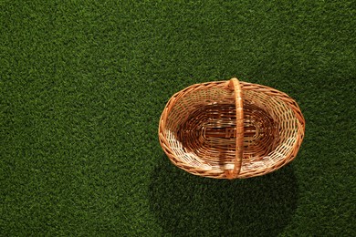 Photo of One picnic wicker basket on green grass, top view. Space for text