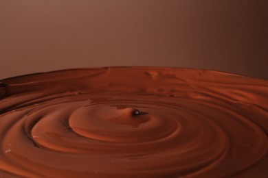 Photo of Delicious melted chocolate on brown background, closeup