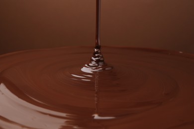 Photo of Pouring delicious melted chocolate on brown background, closeup