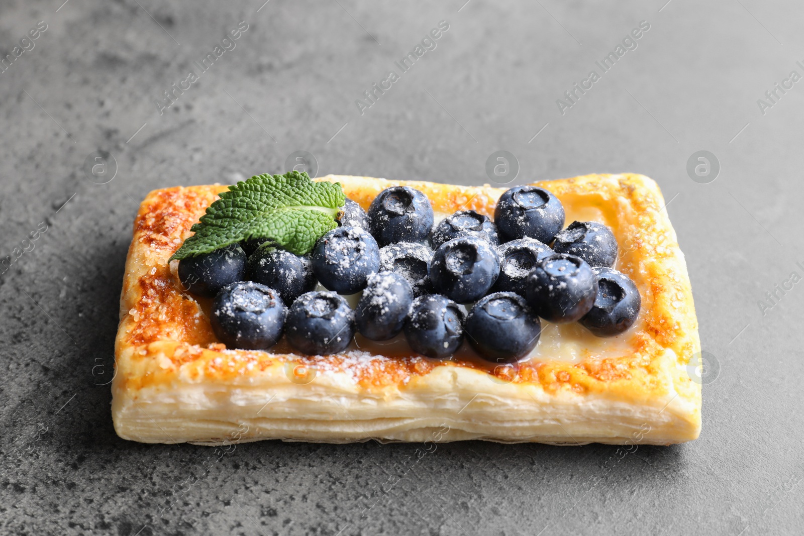 Photo of Tasty puff pastry with blueberries and mint on grey table, closeup