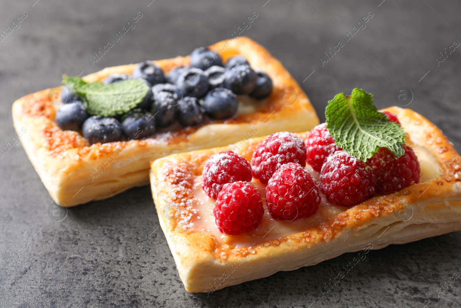 Photo of Tasty puff pastries with berries on grey table, closeup