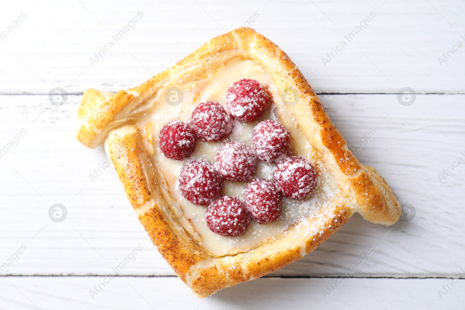 Photo of Tasty puff pastry with raspberries on white wooden table, top view