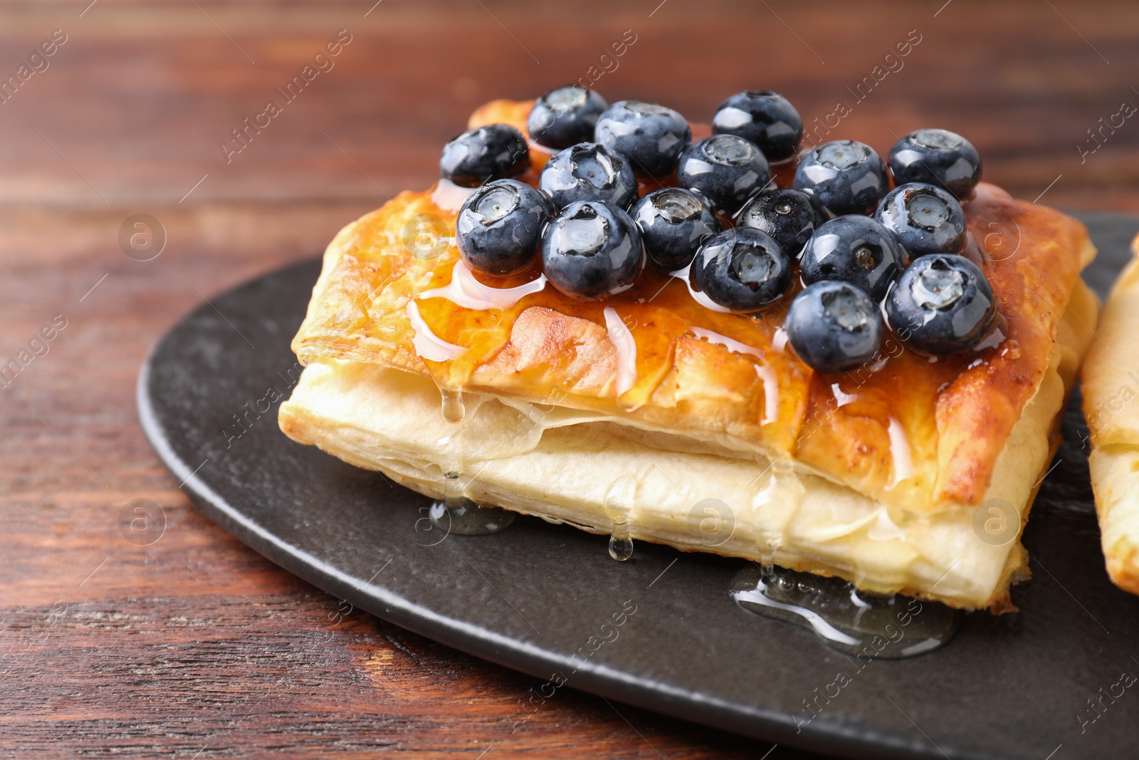 Photo of Tasty puff pastry with blueberries on wooden table, closeup