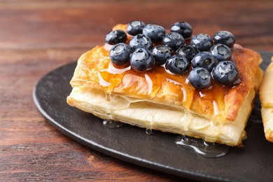 Tasty puff pastry with blueberries on wooden table, closeup