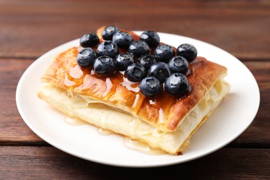 Photo of Tasty puff pastry with blueberries on wooden table, closeup