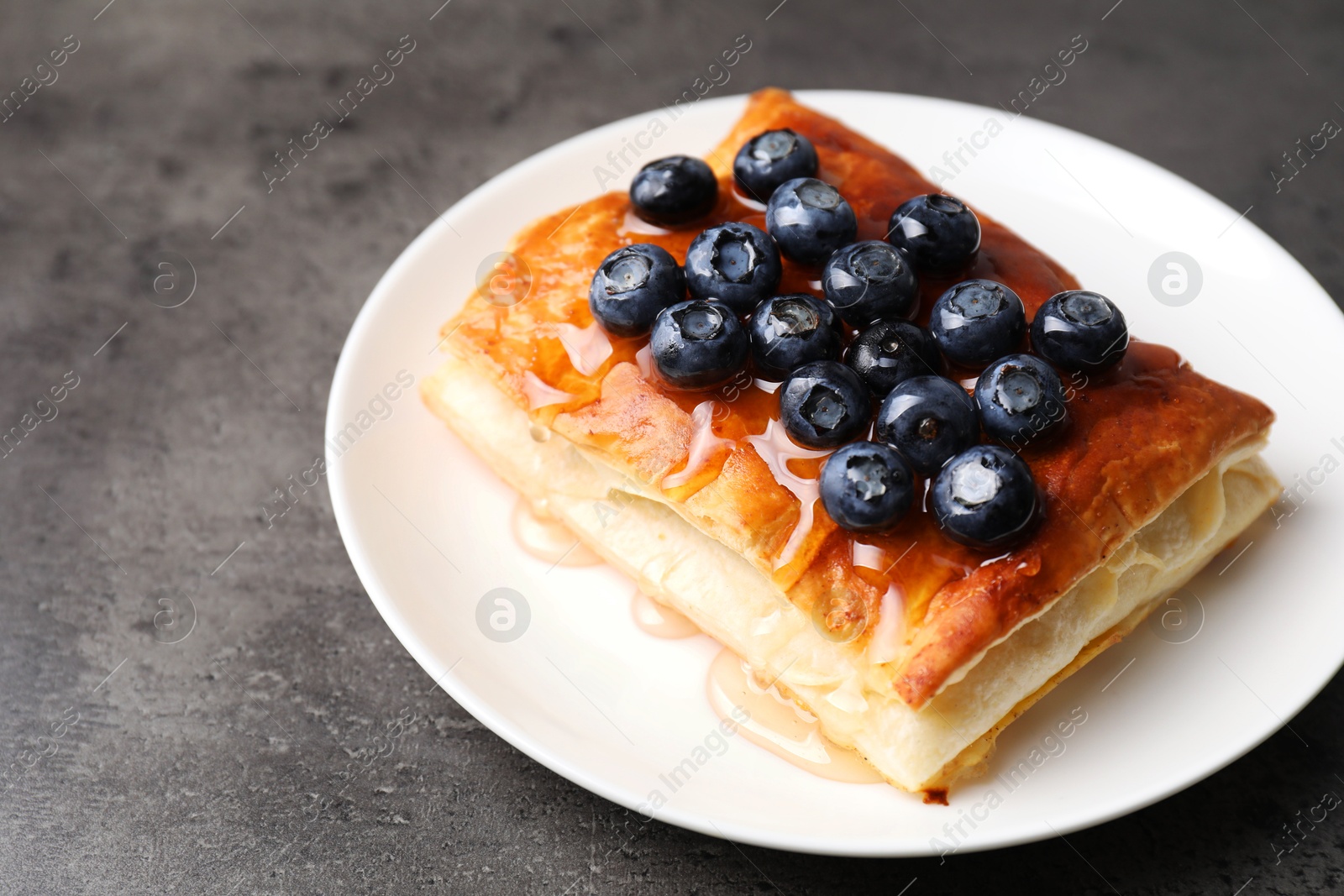 Photo of Tasty puff pastry with blueberries on grey table, closeup