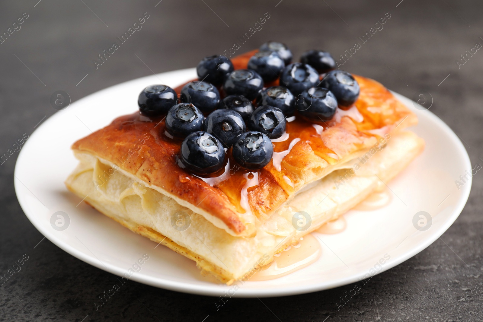 Photo of Tasty puff pastry with blueberries on grey table, closeup