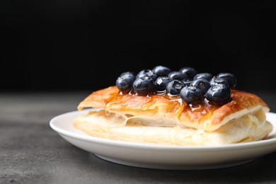 Photo of Tasty puff pastry with blueberries on grey table, closeup