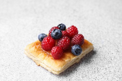 Photo of Tasty puff pastry with berries on light grey table, closeup