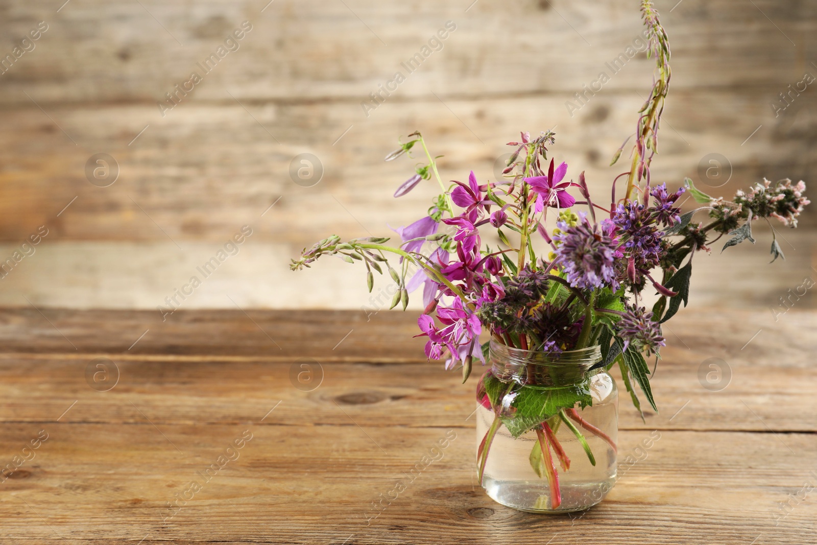 Photo of Bouquet of different healing herbs on wooden table. Space for text