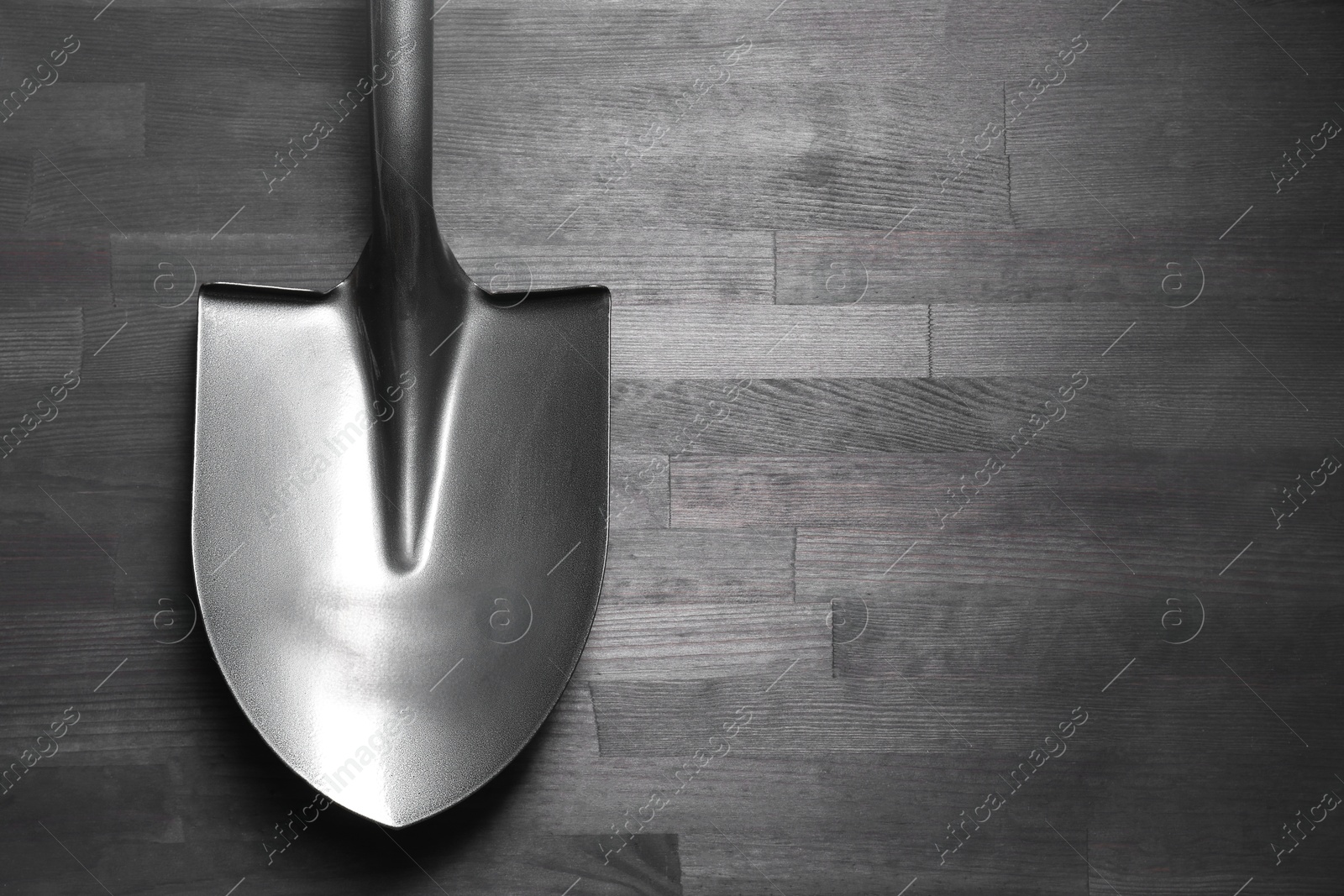 Photo of Metal shovel on black wooden table, top view. Space for text