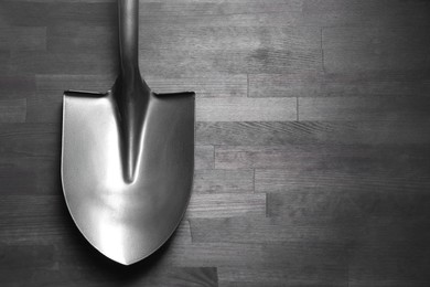 Photo of Metal shovel on black wooden table, top view. Space for text