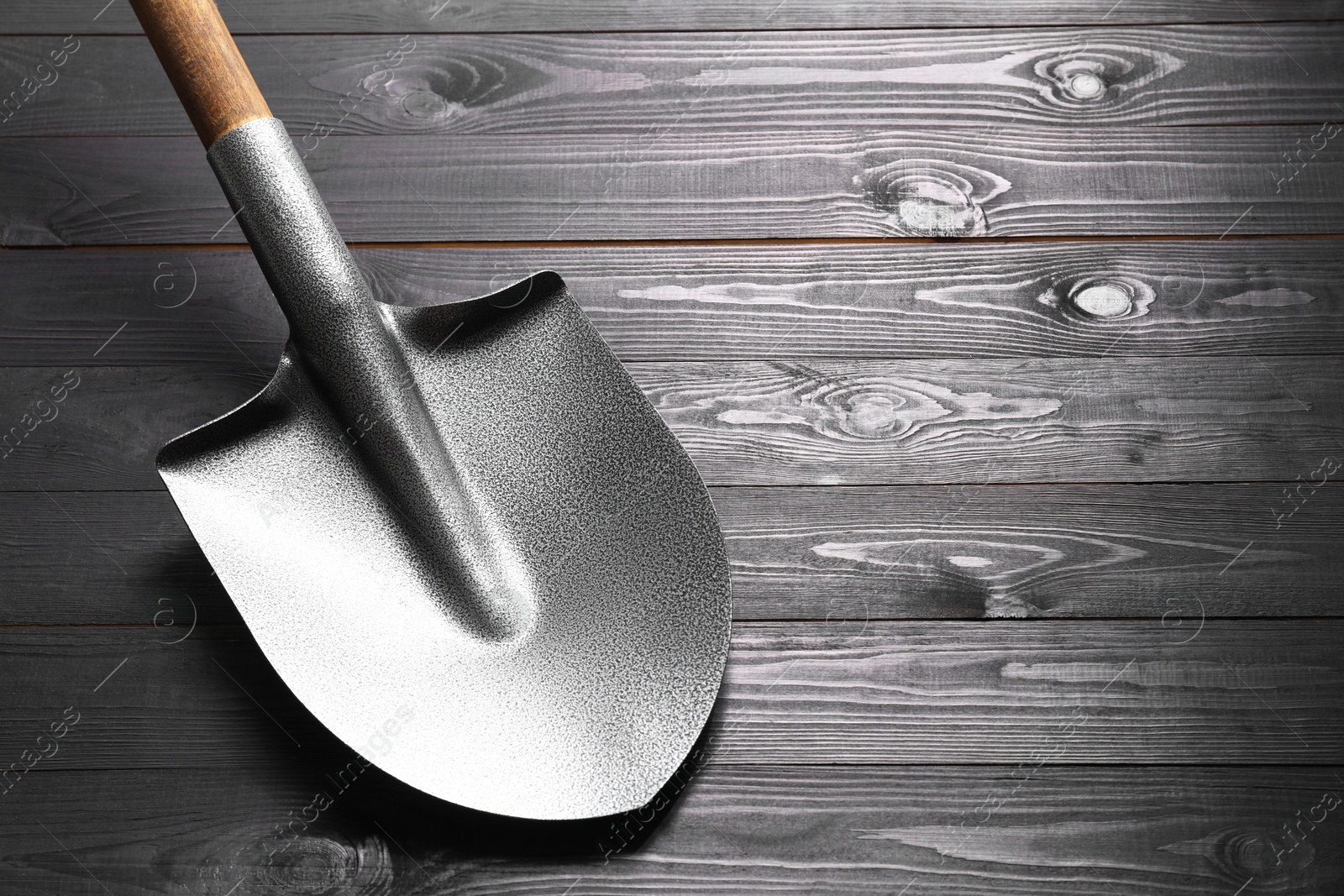 Photo of Metal shovel on black wooden table, space for text