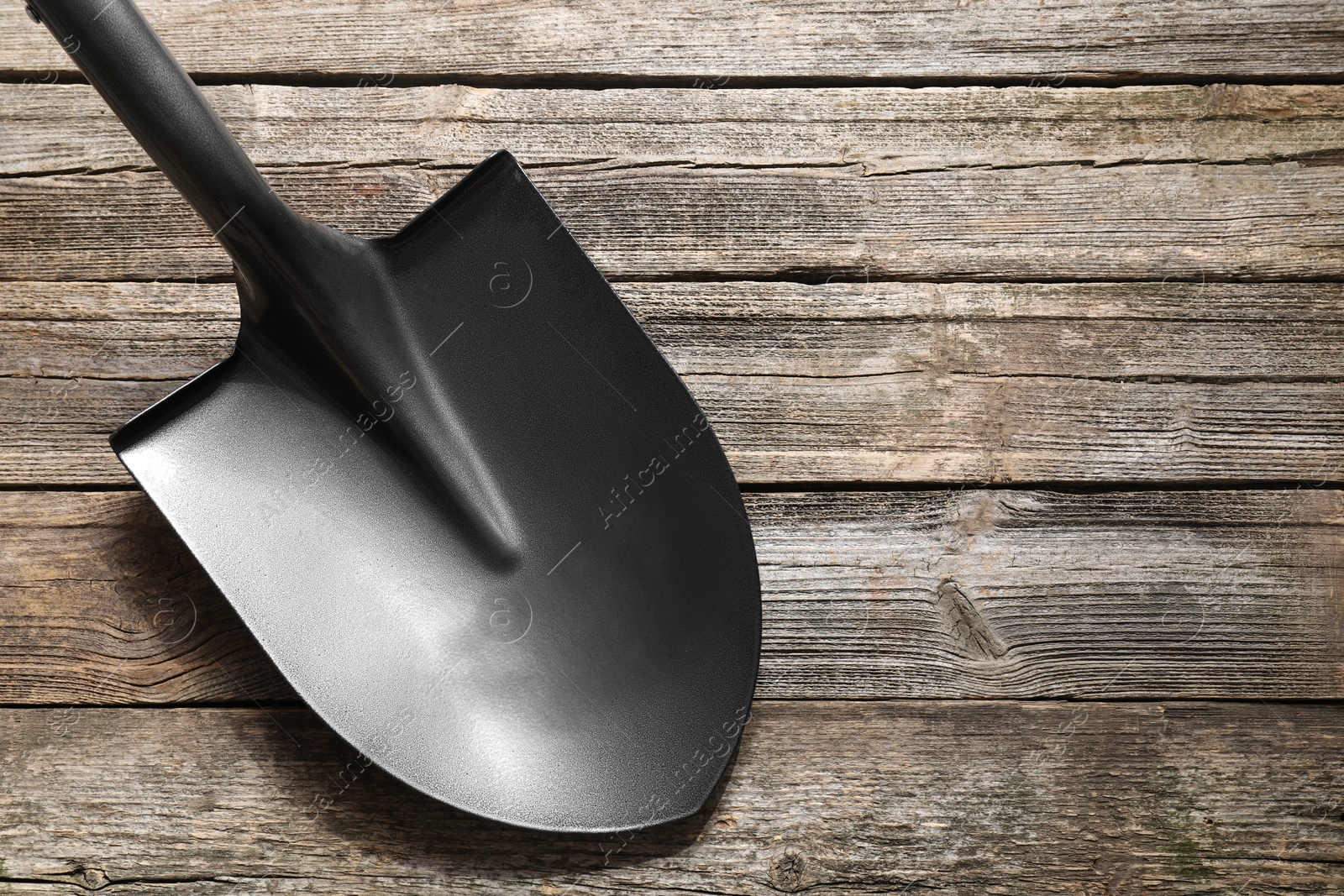 Photo of Metal shovel on wooden table, top view. Space for text